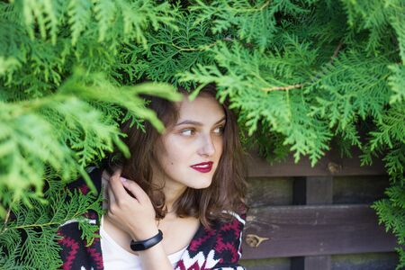 Wooden fence photoset. Girl covered with green tree branches in front of wooden fence.の写真素材