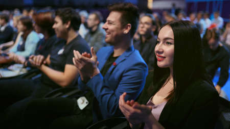 Seminar business meeting applause speaker. Crowd smiling audience active clapping man speech. Happy business woman applaud. Group smile people clap summit. Large auditorium joy applause economic forumの写真素材