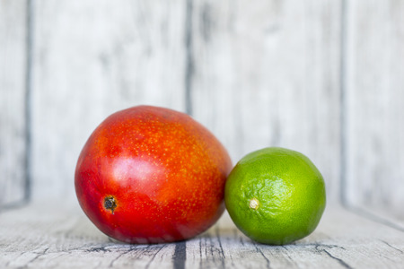Red ripe mango and green lemon on the tableの写真素材