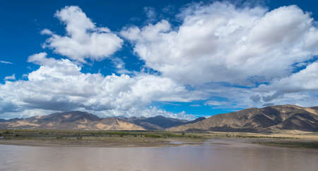 Blue sky, white clouds and autumn woods reflected on the waterの写真素材