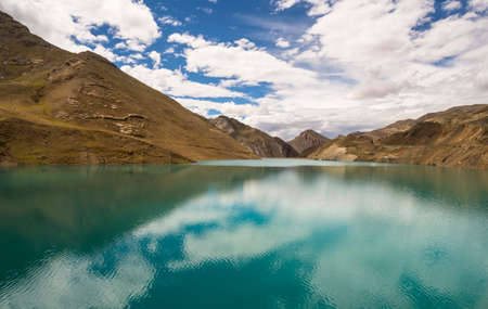 Blue sky, white clouds and autumn woods reflected on the waterの写真素材