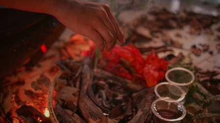 Hands of a young man lighting a candle at a campfire