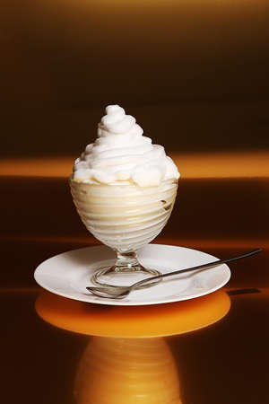 Dessert with creamy cream in a glass vase on brown backgroundの写真素材
