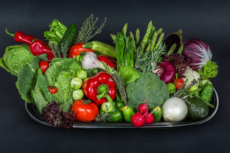 Tray with heap of fresh vegetables on the black background, beautiful colorful autumnの写真素材