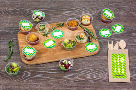 Various dishes in plastic container and wooden cutlery on table, top viewの写真素材