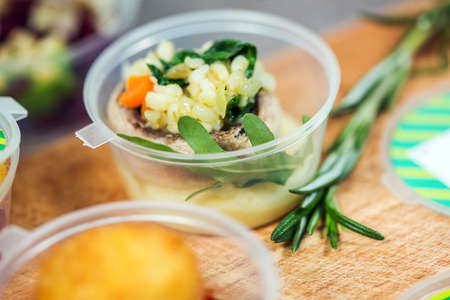 Dishes with fish and rice in plastic container on wooden table. Close-upの写真素材