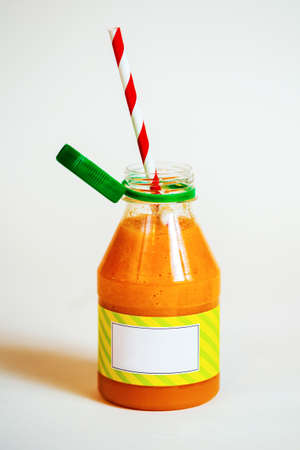 Bottle orange smoothie with straws on white background. Close-upの写真素材