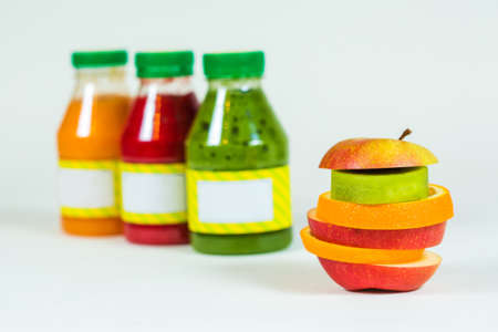 Bottles smoothie with pieces fresh fruit on white background. Close-up