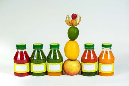 Bottles smoothie with fresh apple, lemon, lime, physalis, raspberries on white backgroundの写真素材