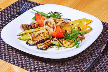 Salad of grilled vegetables on a white plate decorated herbs.の写真素材