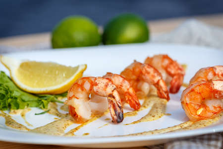 Grilled prawns with sauce and lemon on white plate. Close-upの写真素材