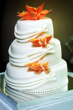 White multi level wedding cake with orange lilies flower decorations.の写真素材