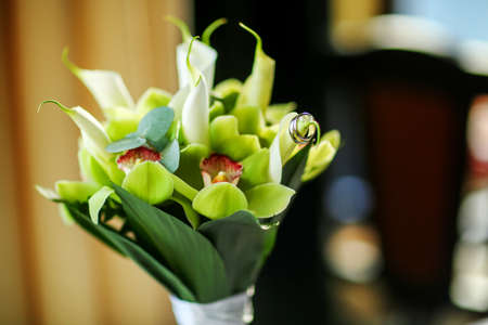 Beautiful golden engagement rings on the tender wedding bouquet.の写真素材