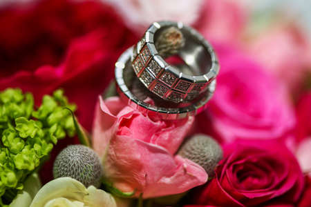 Beautiful shiny wedding rings with diamonds on the pink flowers. Wedding conceptの写真素材