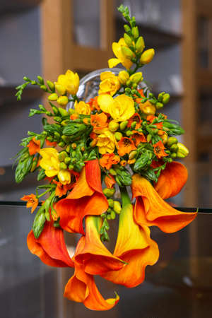 Colorful bouquet of orange calla lilies and other flowers on the table.の写真素材