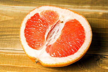 Half grapefruit citrus fruit cut on a wooden background.
