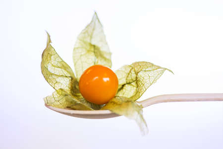 Orange organic physalis in wooden spoon iの写真素材