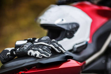 Biker sitting on motorcycle on an empty road, close-up view on hands on handlebars.