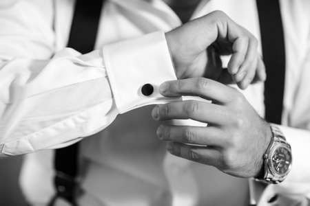 Hands groom wears a metallic silver cufflinks stud. stylish wedding accessories.