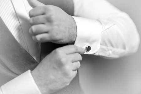Hands groom wears a metallic silver cufflinks stud. stylish wedding accessories.