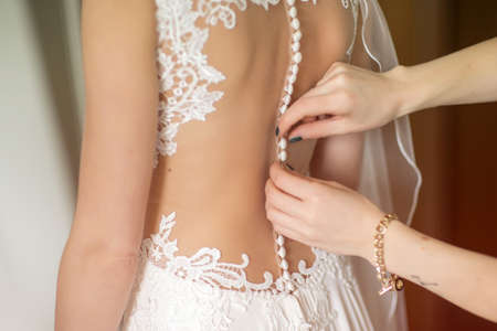 Helping the bride to put her wedding dress onの写真素材