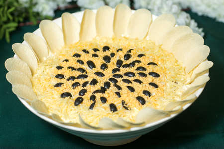Mimosa canned fish salad layers in the shape of a circle with a portion. Angle view