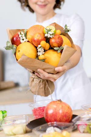 The original unusual edible bouquet of vegetables and fruits in girl hands with cardの写真素材