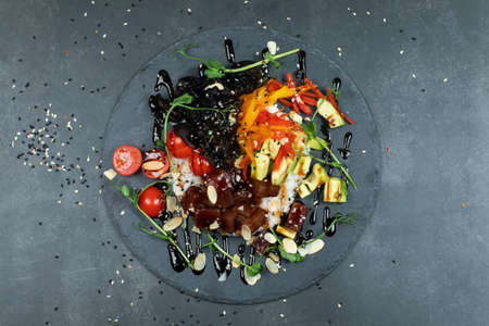 Hawaiian salmon fish poke bowl with rice, radish,cucumber, tomato, sesame seeds and seaweeds. Buddha bowl. Diet foodの写真素材