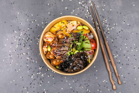Poke bowl with chicken and vegetables on the white table.
