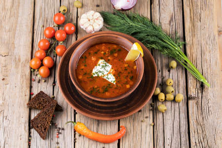 Dish of russian hodgepodge soup and other food on a wooden table.の写真素材