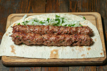 lula kebab with herbs on a wooden surface