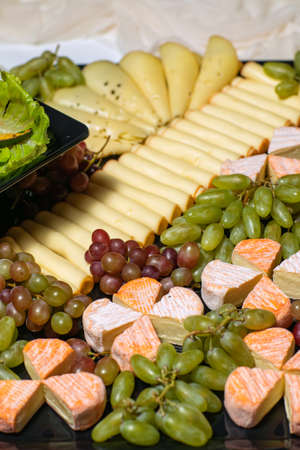 various types of cheese on wooden cutting board, top viewの写真素材