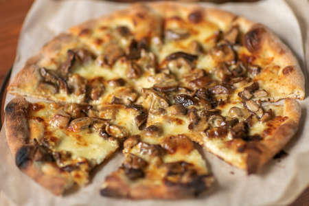 Mushroom pizza with addition mozzarella cheese and herbs on a wooden table,の写真素材