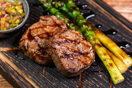 Veal medallions with green beans and chilli pepper on a plate on a wooden backgroundの写真素材