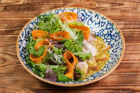 Pumpkin salad with chicken and arugula on a vintage plate over dark blue slate,stone or concrete background.の写真素材