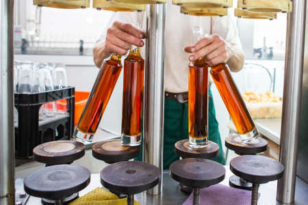Unlabeled glass bottles in bottling machine at modern wineryの写真素材