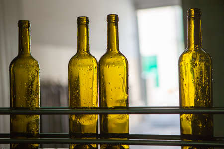 Unlabeled glass bottles in bottling machine at modern wineryの写真素材