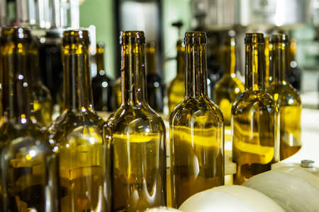 Unlabeled glass bottles in bottling machine at modern wineryの写真素材