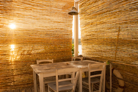 Wooden table of a rustic sea restaurant in a small fishing village at sunriseの写真素材