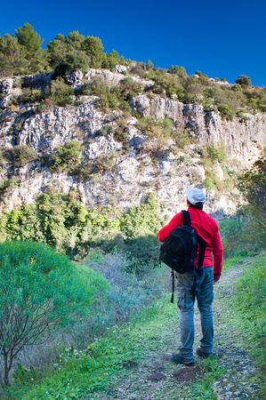 Hiker walking along the trails of the Anapo valley, by the rocky necropolis of Pantalicaの写真素材