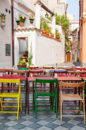 Characteristic colored tables of a Restaurant/pizzeria in the main square of Castelmola, a small touristic village near Taorminaの写真素材