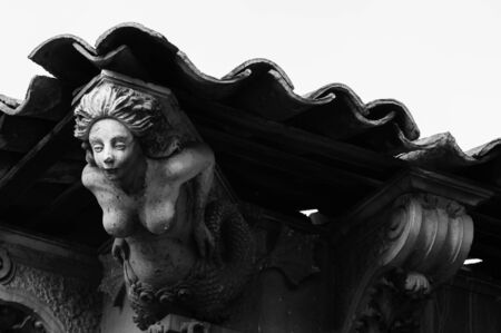 Sculpture of a mermaid used as architectural element under a tile roof of an old baroque palaceのeditorial素材