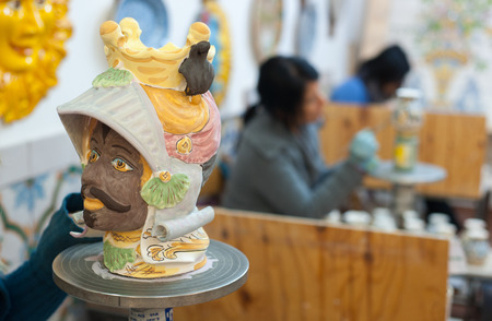 Ceramic head of an arab soldier being finished by a decorating artisan of Caltagirone in a local workshop of the townの写真素材