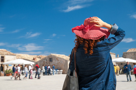 A tourist with a red hat looking at the main square of the small village Marzamemi, South East Sicilyの写真素材