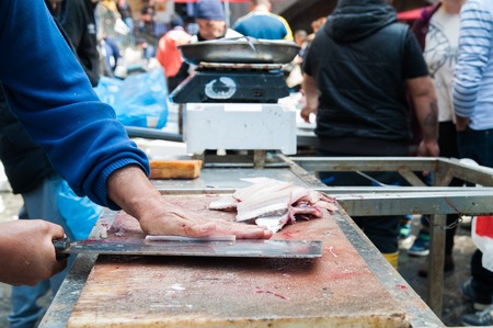 Fish seller in the fish market of Catania in Sicily while cutting paddle fish into slicesの写真素材