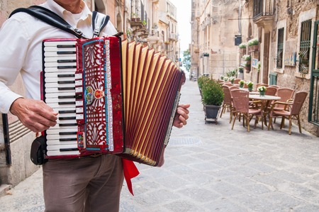 Accordion musician playing along the alleys of the old part of Syracuse Ortigiaの写真素材