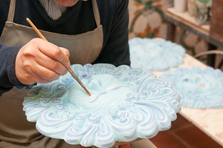 Artist decorating a typical blue ceramic sun in its studio in Caltagirone