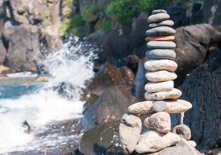 Stone piles made along a beach and the crashing waves in the backgroundの写真素材