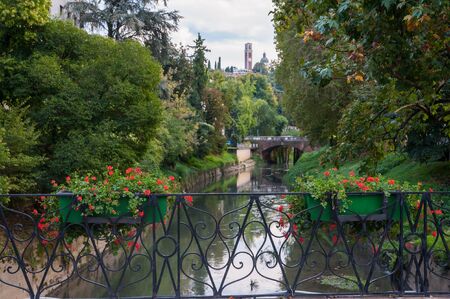 The flowered iron balcony of Furo bridge, Vicenza, with a view of Retrone river and Mount Berico in the distanceの写真素材