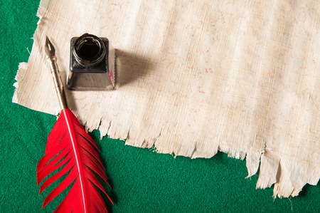 Red quill pen and black inkwell on a papyrus sheetの写真素材